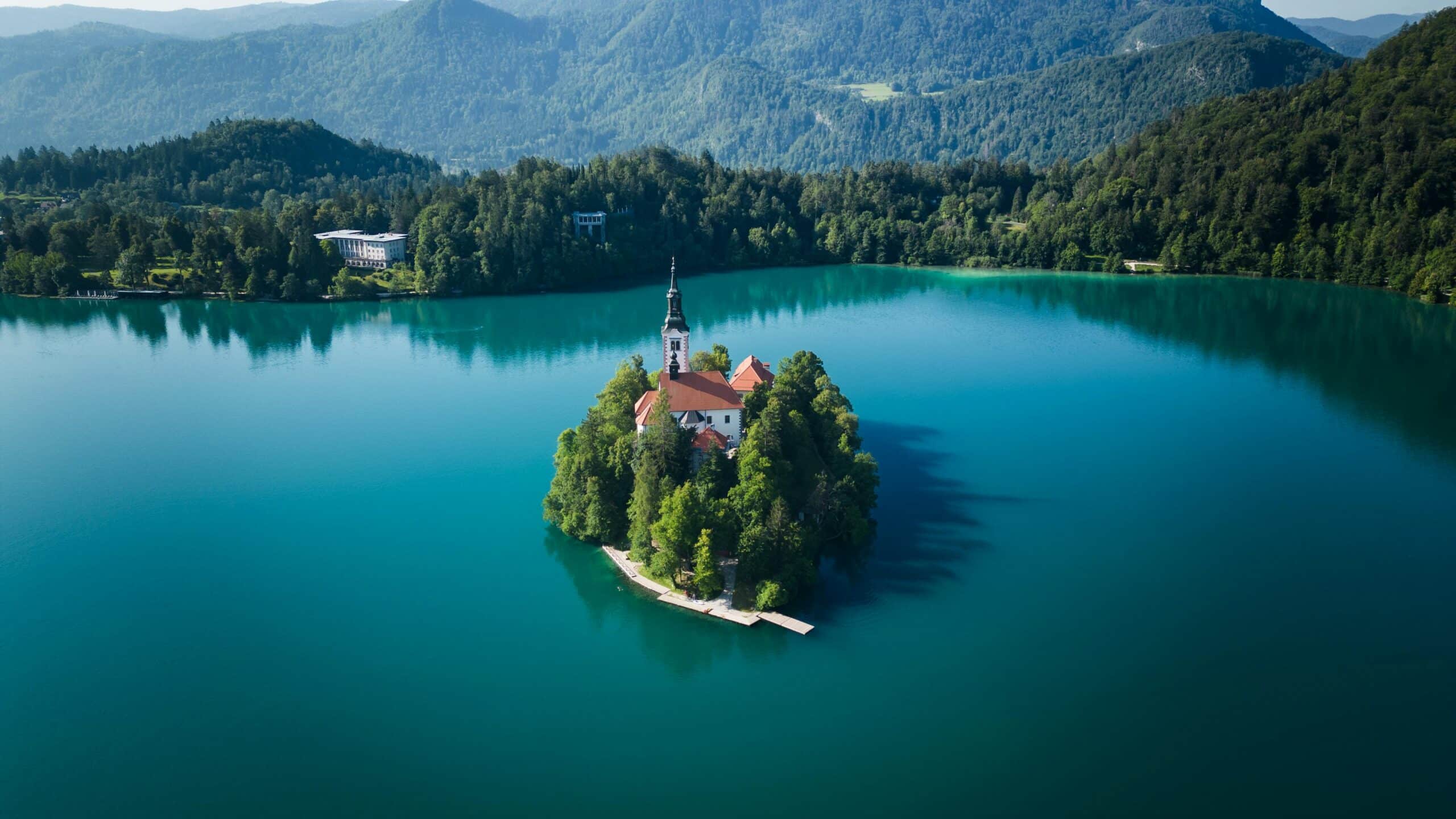 A breathtaking aerial view of Bled Island and its church in Slovenia, surrounded by vibrant blue waters.