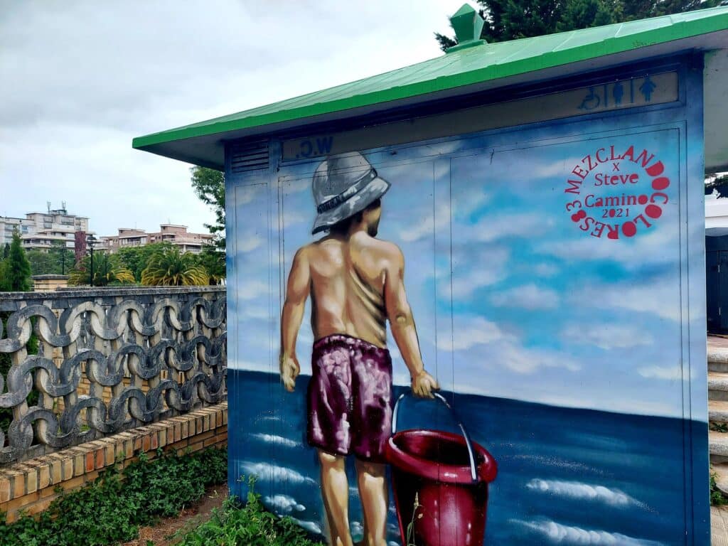 caseta de servicios publicos, decorada con pintada de un niño en la playa. playa de Laredo