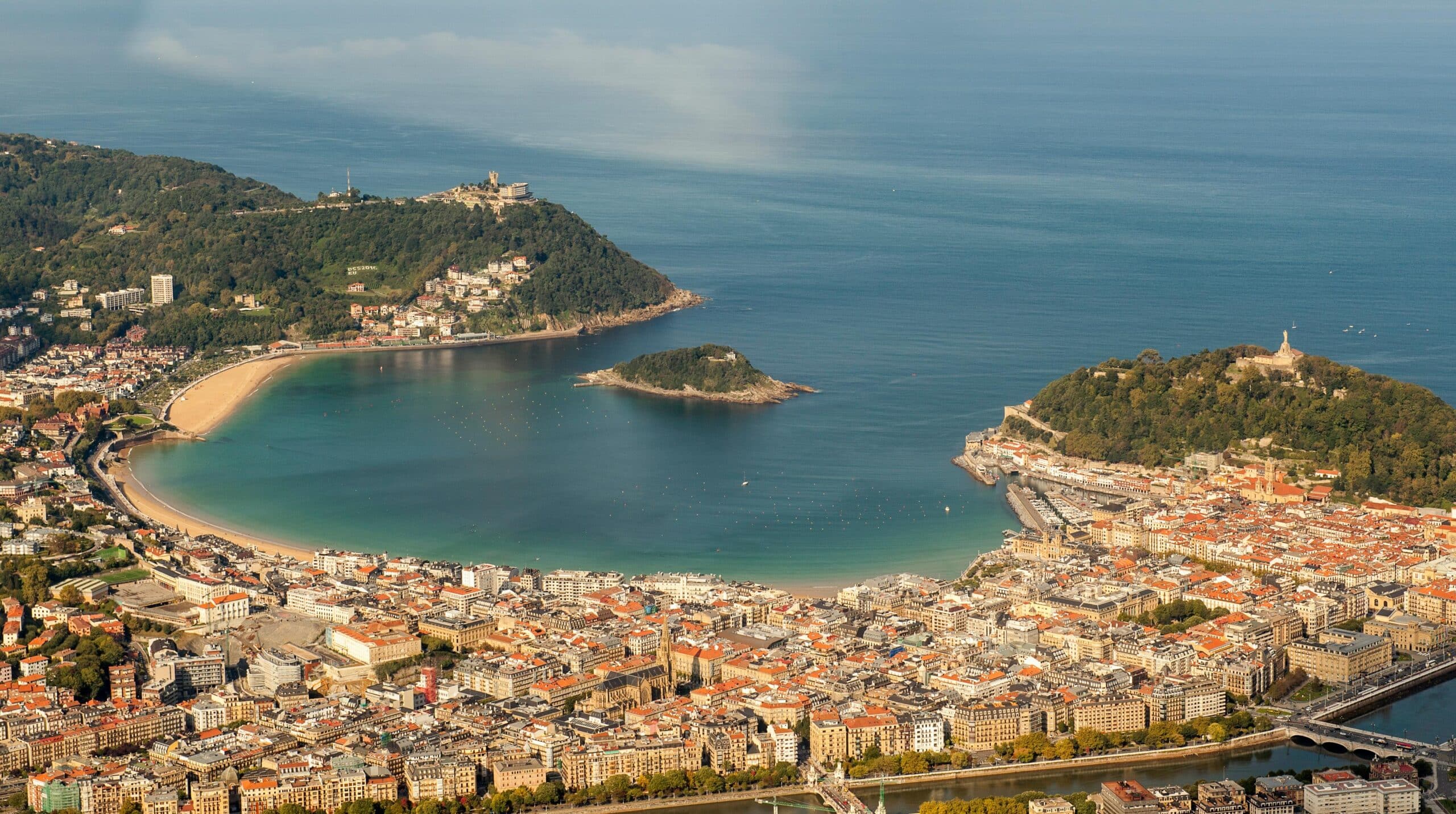 A stunning aerial view of La Concha Bay, San Sebastián, with lush hills and cityscape.