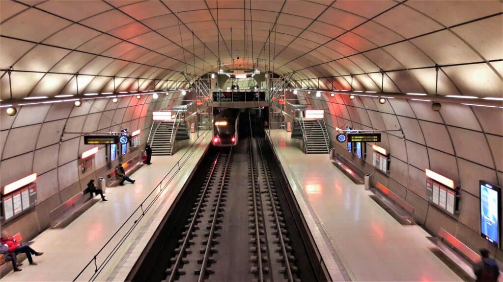 A subway train arrives at a modern Bilbao metro station, featuring sleek architecture.